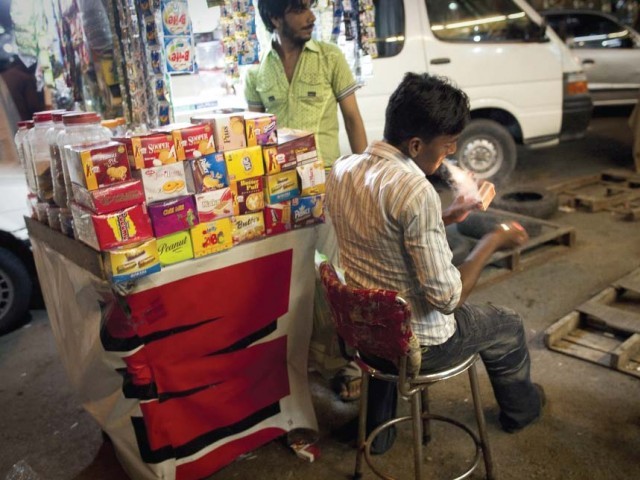 Sex worker Nadeem, who pimps 10 teenage sex workers aged 14 to 18, lights a cigarette in Saddar on July 25.