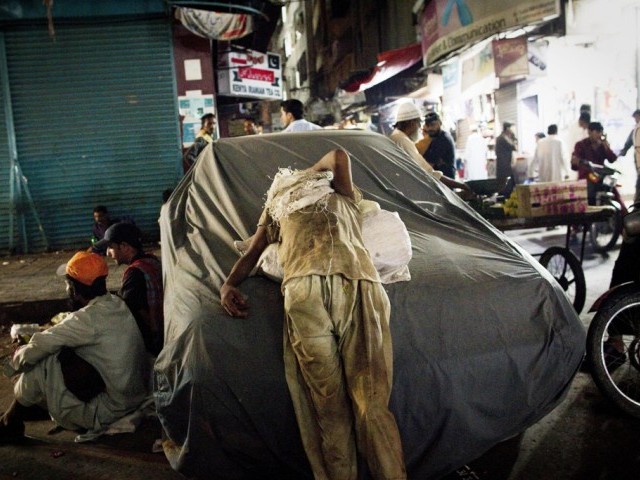 In this picture taken on July 22, 2011 a Pakistani street child and scavenger rests on a car in downtown Karachi