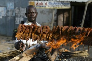 A man arranges sticks of meat on a mud p