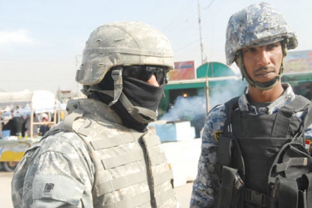 An Iraqi interpreter, left, translates a conversation between an Iraqi National Police officer and U.S. soldiers in Baghdad.