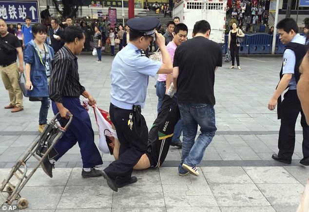 In this photo taken by a mobile phone, a suspected assailant is taken away after being subdued in an attack at a railway station in Guangzhou 