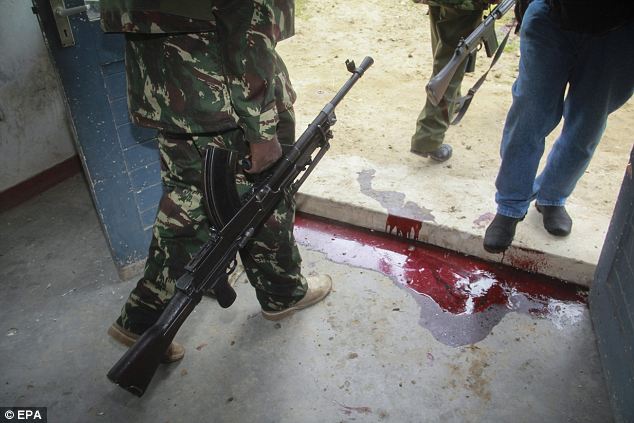 A police officer walks past blood stains on the ground at the Gamba police station in Gamba 