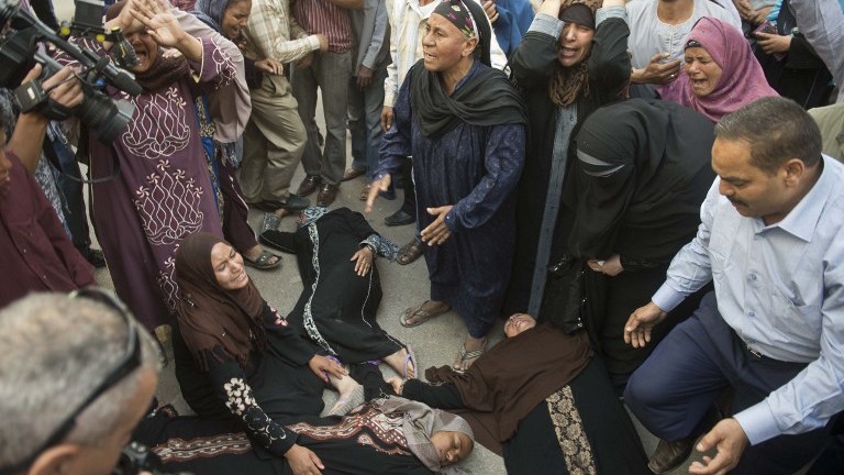 Egyptian women faint outside the courtroom in Egypt's southern province of Minya after an Egyptian court sentenced Muslim Brotherhood spiritual leader Mohamed Badie and others to death,