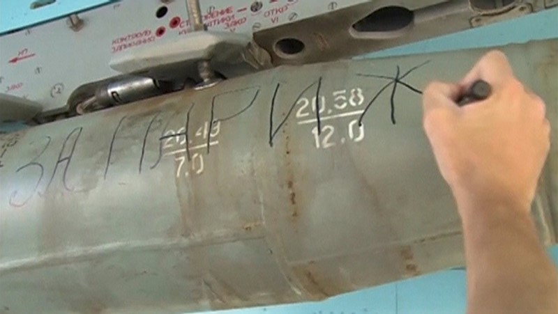 A Russian ground crew member writes 'For Paris' on the side of a bomb destined for Syria 
