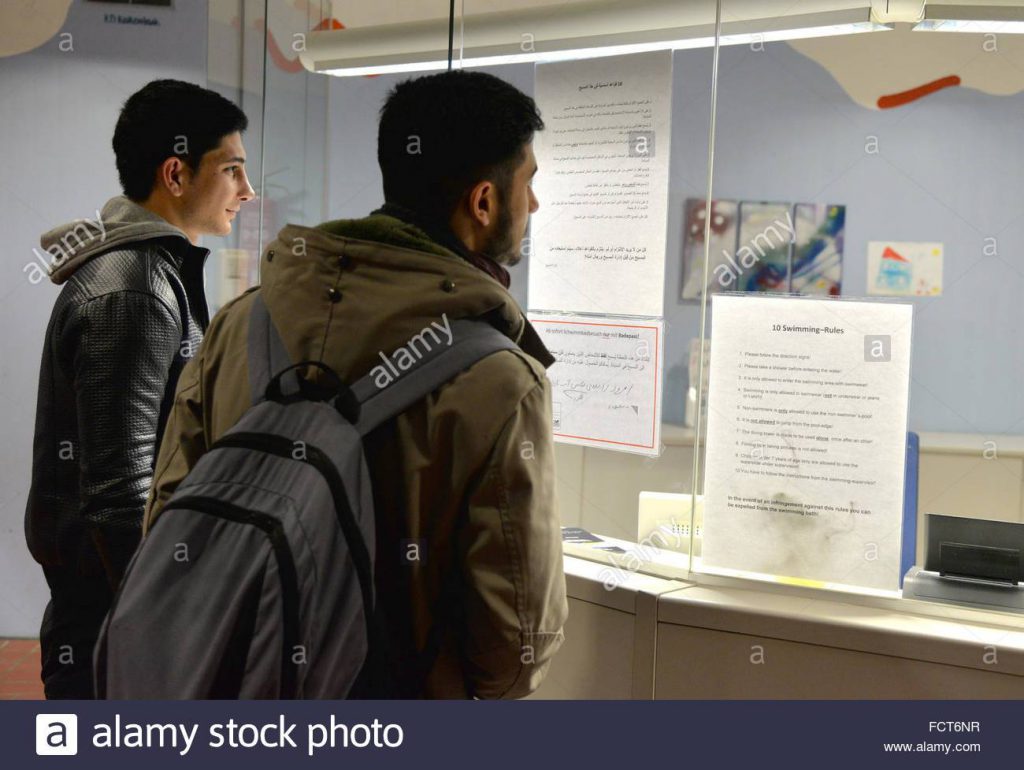 MUSLIM refugees Mohsen and Ali (l) reading the pool rules written in German, Arabic and English in the swimming pool in Hermeskeil, Germany, 21 January 2016. Both own a swimming pass, which allows them to use the pool
