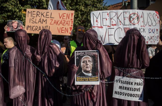 Protesters wearing a burkha hold banners during a demonstration against German Chancellor Angela Merkel on August 25, 2016 in Prague